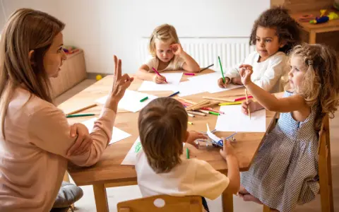 Bambini disegnano e giocano con un aereo, guidati da un'insegnante. Un esempio di come le scienze della formazione sbocchi in attività creative e formative.