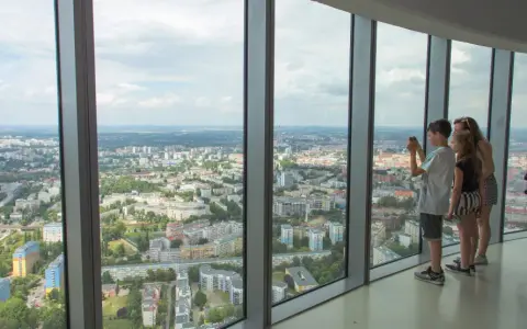 Widok z tarasu widokowego Sky Tower. Rodzina podziwia panoramę miasta, doceniając jego ogromną wysokość.