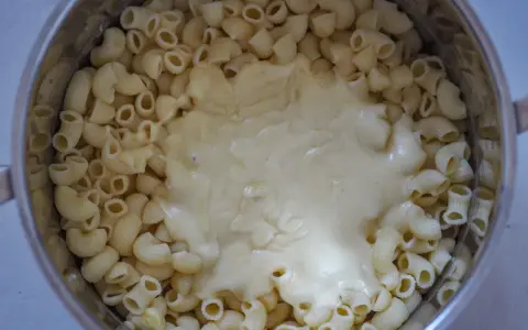Gęsty, kremowy sos serowy otula makaron w garnku, tworząc pyszny makaron mac and cheese.