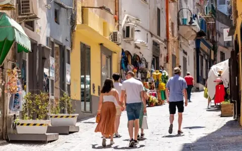 Passeggiata in un vicolo di Procida, tra negozietti colorati e case bianche. Perfetto per capire come muoversi a Procida a piedi.