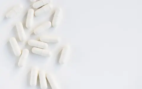 Vita kapslar utspridda på en vit yta. Kan dessa orsaka l-glutamin biverkningar?