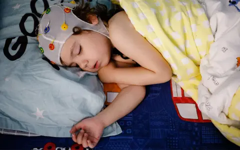 Dziecko śpi w czepku z elektrodami. To kluczowy moment, by dowiedzieć się, jak przygotować dziecko do badania EEG we śnie.