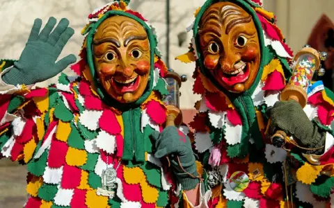 Due maschere di carnevale in Italia, con costumi colorati e volti grotteschi, salutano festanti.