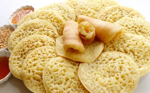 Assiette de crêpes mille trous, garnies de miel et de cacahuètes concassées. Un délice à déguster !