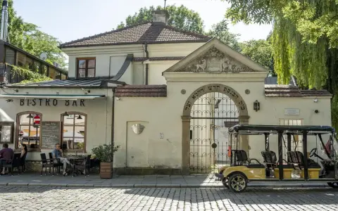 Kazimierz, Kraków. Bistro Bar i zabytkowa brama z hebrajskimi napisami. Obok żółty meleks, idealny na zwiedzanie.