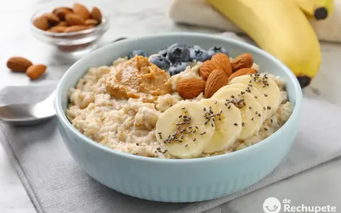 Avena cremosa con plátano, arándanos, almendras y mantequilla de maní. Una guía visual de como cocinar avena para un desayuno nutritivo.