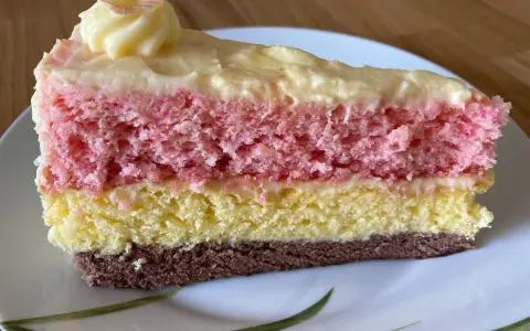 Ein Stück bunte, einfache Torte mit Puddingcreme. Schichten aus Schoko-, gelbem und rosa Biskuit, bedeckt mit cremiger Puddingfüllung.