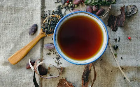 Une tasse de thé ambré, une cuillère de feuilles de thé, des fèves de cacao et des épices. Une invitation à découvrir les rooibos bienfaits.