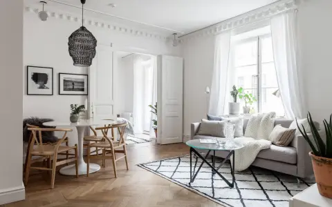Ljust och luftigt vardagsrum med matbord och inspiration från skandinavisk design. En rund vit matplats med trästolar möter en soffgrupp med mysiga textilier.