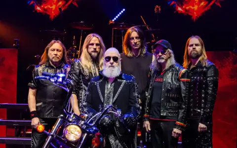 Judas Priest Polska: zespół w skórzanych kurtkach z ćwiekami, z motocyklem na scenie.