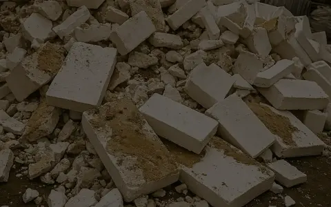 Stos białych, połamanych kawałków styropianu z widocznymi śladami ziemi.