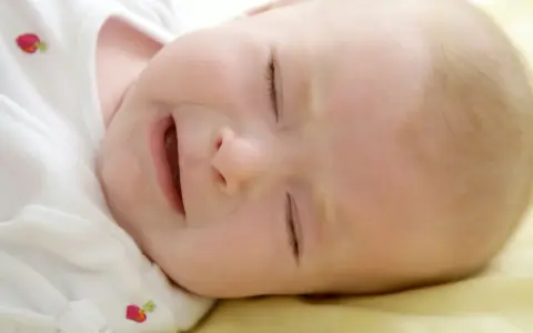 Słodkie niemowlę płacze przez sen, z otwartymi ustami i zamkniętymi oczami.