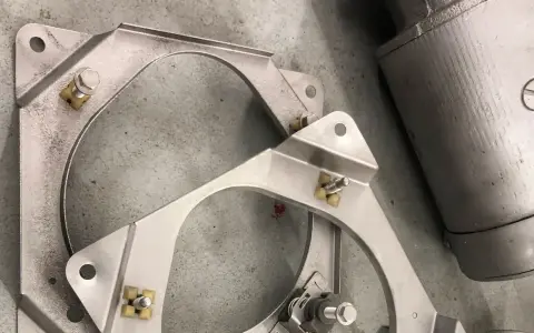 Metalowe elementy po obróbce szkiełkowanie a piaskowanie. Widać ślady po śrubach i mocowaniach.