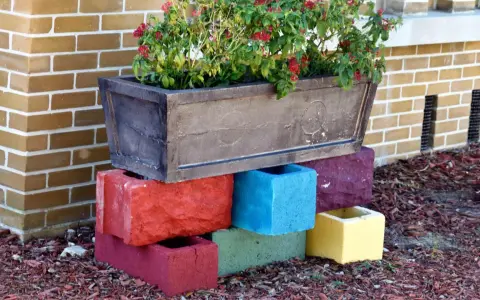 Un bac à fleurs sur des blocs de béton colorés, une idée de **diy jardin** pour rehausser vos plantes.