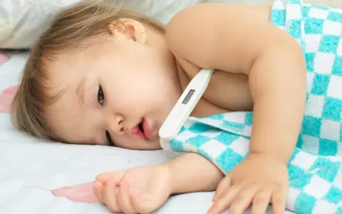 Małe dziecko z gorączką, termometr pod pachą. Trwa 3 dniówka u dziecka, które potrzebuje odpoczynku.