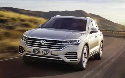Elegancki Volkswagen Touareg, jeden z wielu imponujących volkswagen modele, pędzi po krętej drodze wśród wzgórz.