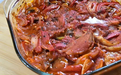 Pyszna karkówka po cygańsku w sosie pomidorowym z cebulą i papryką, zapiekana w naczyniu żaroodpornym.