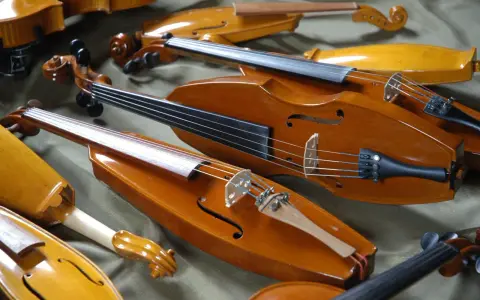 Kolekcja zabytkowych, drewnianych instrumentów smyczkowych. Te średniowieczne instrumenty, z ich ciepłym, lakierowanym wykończeniem, czekają na muzyków.