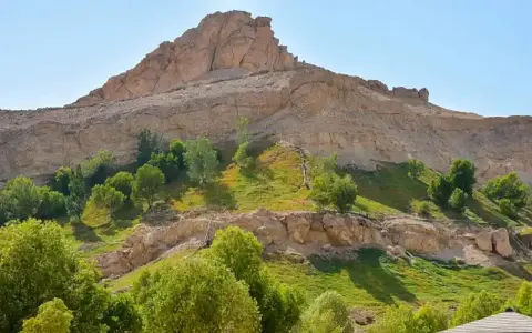 Grüne Oase am Fuße eines Felsmassivs bei Al Ain. Üppige Vegetation kontrastiert mit der trockenen Berglandschaft.