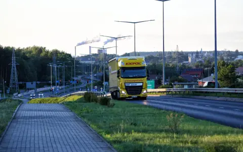 Żółta ciężarówka EXPOL jedzie drogą, symbolizując mobilność i wyzwania związane z pakietem mobilności a umową zlecenie.