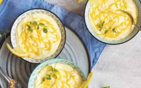 Tre coppette di deliziosa mousse al limone, guarnite con scorza di limone e menta fresca.
