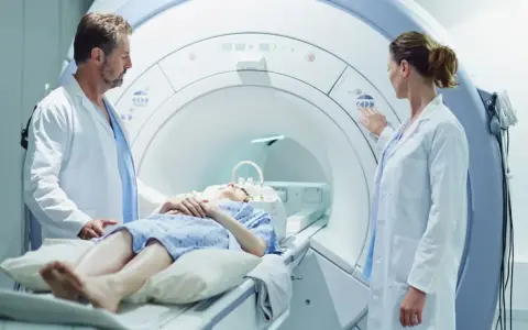 Pacjentka leży w aparacie do rezonansu magnetycznego, a lekarze przygotowują badanie z kontrastem.