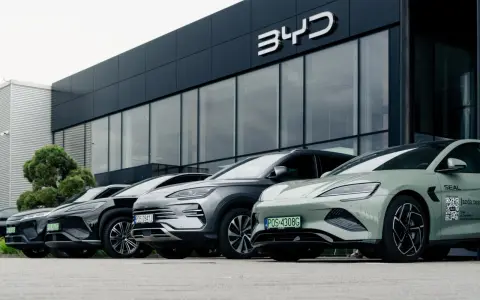 Vari modelli di auto BYD parcheggiati davanti a uno showroom moderno.