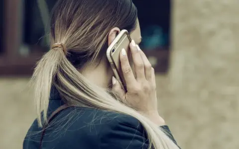 Kobieta rozmawia przez telefon, martwiąc się, czy pracodawca może odmówić urlopu na żądanie.