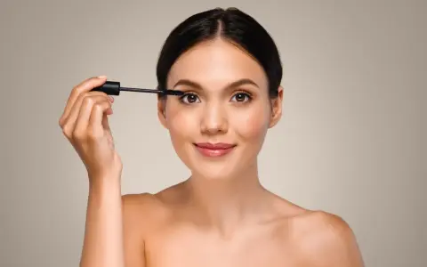 Mujer aplicando máscara de pestañas, un paso esencial para aprender como aplicar sombras de ojos principiantes y realzar la mirada.
