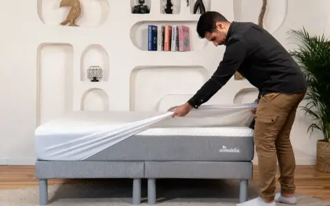 Un homme installe une housse sur un matelas, assurant ainsi sa protection.
