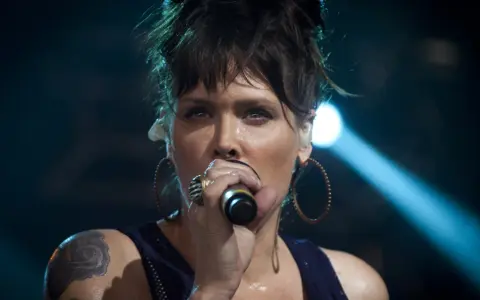 Beth Hart z tatuażem na ramieniu, w okrągłych kolczykach, śpiewa do mikrofonu. Choć nie widać jej dzieci, jej energia na scenie jest jak dla nich.