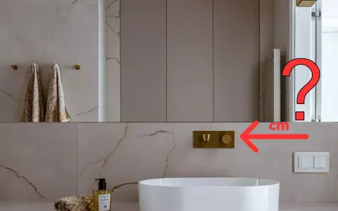 Złota bateria podtynkowa nad białą umywalką. Jaka powinna być idealna wysokość wylewki nad umywalką?
