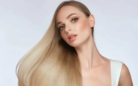 Blonde Frau mit glänzendem Haar, das durch Proteine gestärkt wurde.