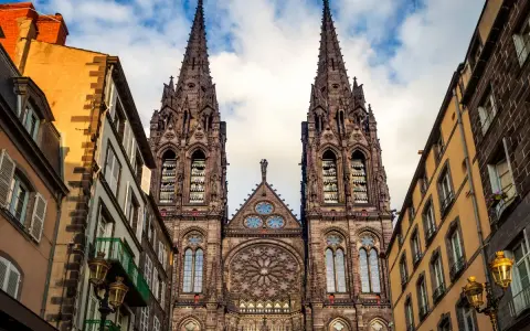 La cathédrale de Clermont-Ferrand, une des plus belles cathédrales de France, se dresse fièrement entre des immeubles anciens.