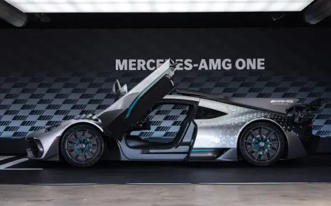 Srebrny Mercedes-AMG ONE z otwartymi drzwiami i maską, prezentujący futurystyczny design i sportowe osiągi.