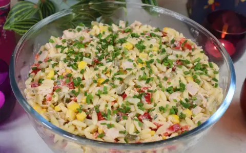 Pyszna sałatka z makaronem orzo, kukurydzą, papryką i kurczakiem, posypana szczypiorkiem. Idealna na letnie dni.