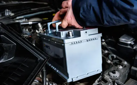Mano che inserisce una nuova batteria. La batteria della macchina serve per avviare il motore e alimentare i sistemi elettrici.