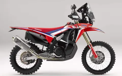 Czerwono-biały motocykl Honda CRF 450 Rally z czarnymi akcentami, gotowy na rajdowe wyzwania.