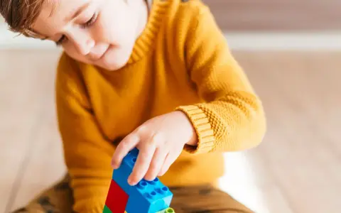 Niño concentrado jugando con bloques de construcción. Un ejemplo de cómo el juego puede ayudar a superar un retraso madurativo y TDAH.