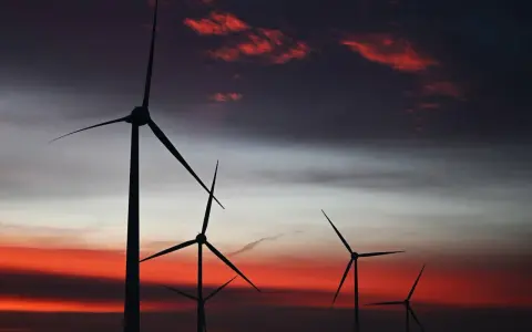 Silhouetten von Windkraftanlagen in den Niederlanden vor einem dramatischen Sonnenuntergang mit roten Wolken.