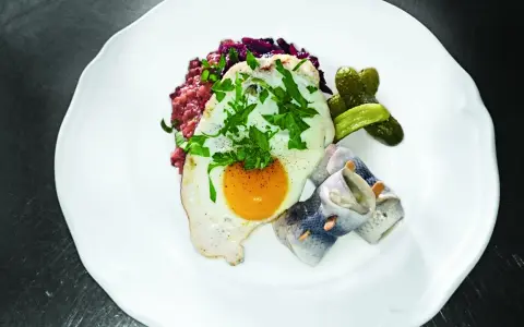 Labskaus mit Spiegelei, Rollmops und Gewürzgurken. Die Herkunft dieses norddeutschen Gerichts ist Seefahrer-Tradition.