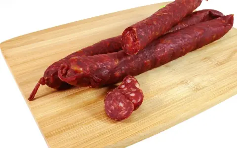 Trzy kawałki pikantnego chorizo na desce. Zastanawiasz się chorizo co to? To aromatyczna, suszona kiełbasa.
