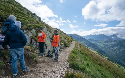 Grupa turystów na skalistej ścieżce w Tatrach. Czy trasa na Kasprowy Wierch jest trudna? Widok na góry i chmury.