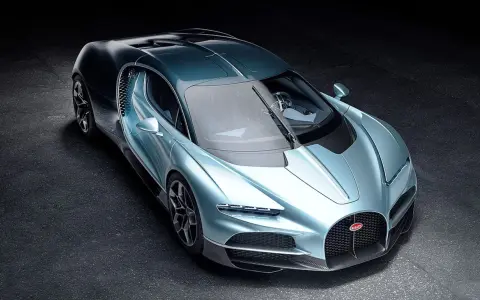 Ein neuer Bugatti in schimmerndem Blau steht auf dunklem Untergrund. Sein Design ist aerodynamisch und luxuriös.