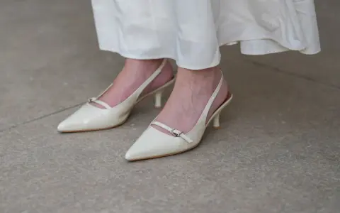 Eleganckie, kremowe szpilki z paskiem na pięcie, idealne do letnich sukienek. Niewidoczne skarpetki do szpilek zapewniają komfort.
