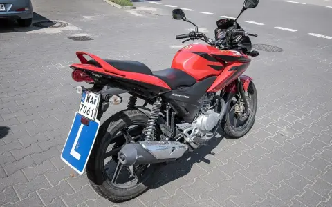Czerwony motocykl Honda CBF125 z tablicą "L" i numerem rejestracyjnym WA7 7061, gotowy do nauki jazdy na prawo jazdy a1.