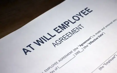 Close-up of an "At Will Employee Agreement" document, illustrating what does at-will employment mean: either party can terminate the relationship at any time.