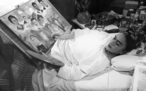 Frida Kahlo målar i sängen, omgiven av sina porträtt av familj och vänner, kanske sina syskon.