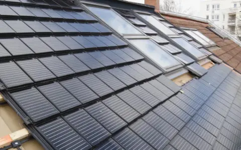 Dachziegel mit integrierten Solarzellen, die eine moderne Alternative zu herkömmlichen Ziegeln darstellen. Die Frage "was kostet ein Dachziegel" wird hier durch die innovative Technologie beantwortet.