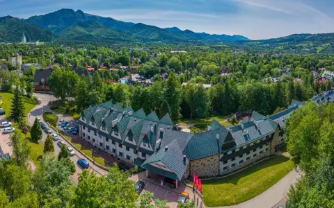 Widok z lotu ptaka na hotel Antałówka w Zakopanem, otoczony zielenią i górami w tle.